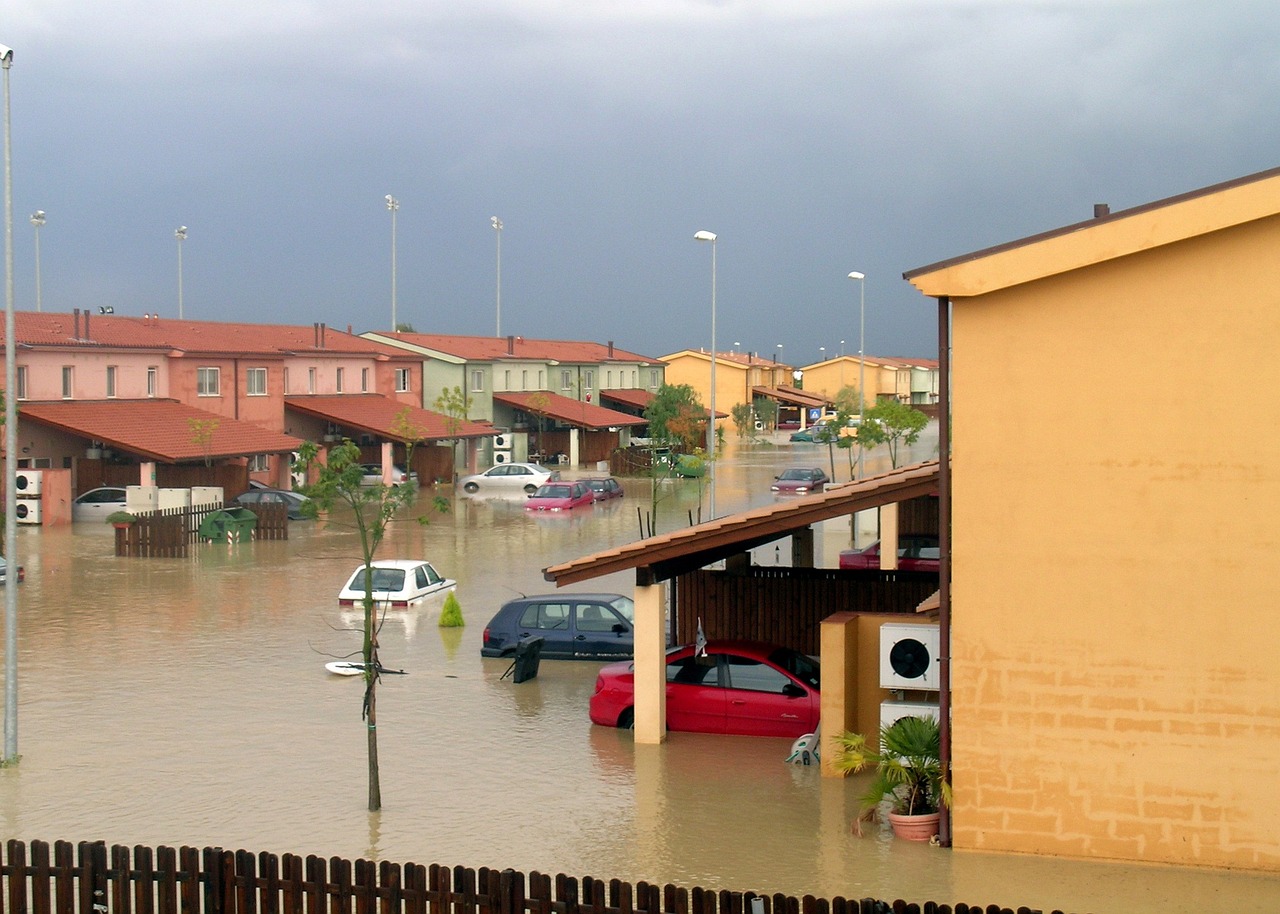 Floodwaters engulf a residential community, with homes submerged and cars floating helplessly in front yards