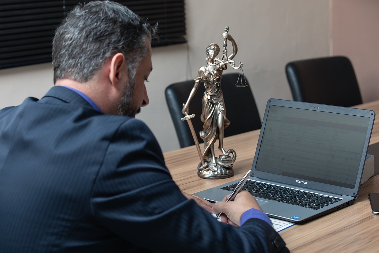 Lawyer working on laptop with Statue of Justice in background