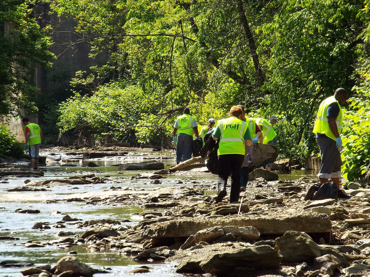 Cleanup crew in protective gear collects waste and debris from contaminated stream.