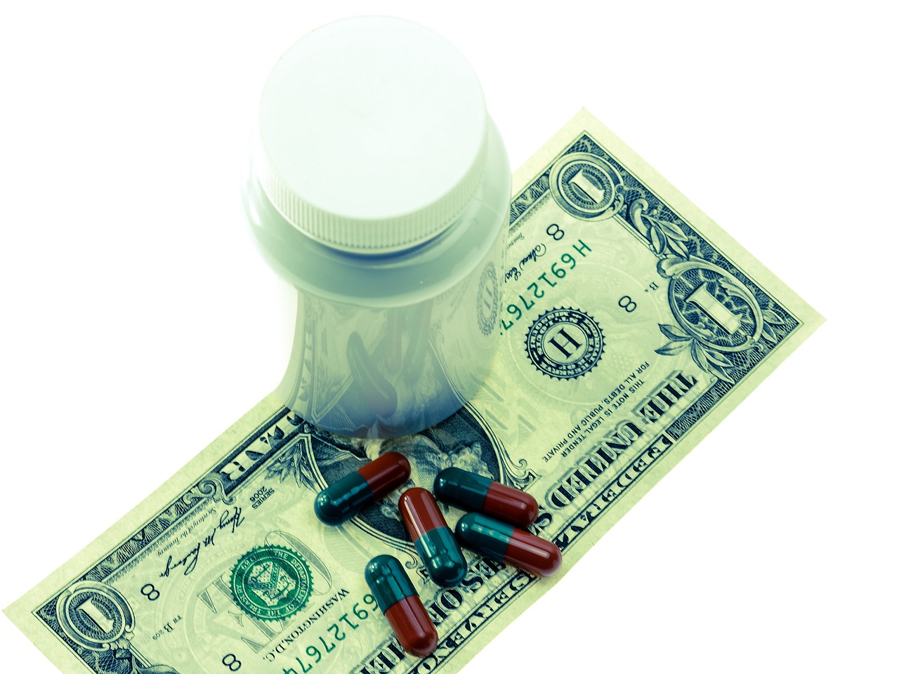 Dollar bill with vial and scattered pills, illustrating workers' comp medical costs