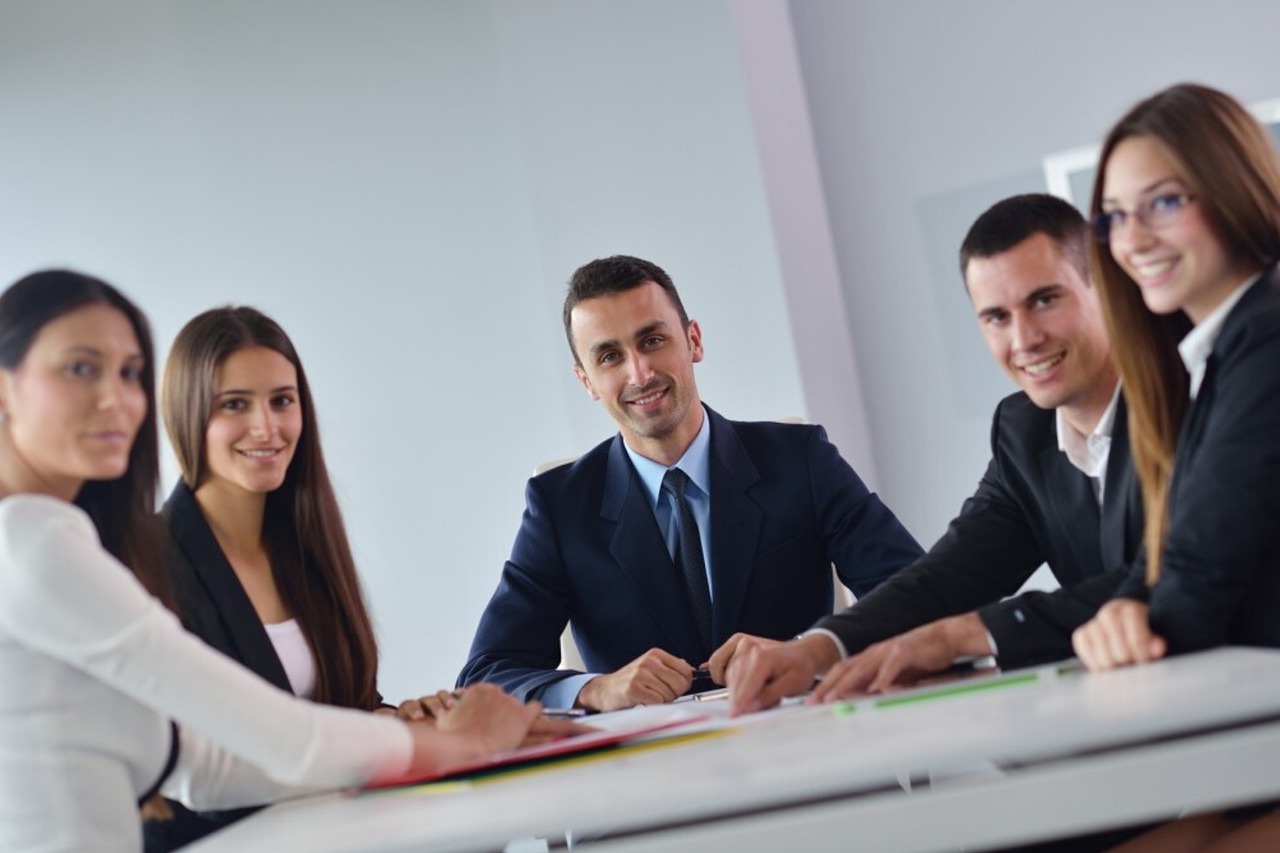 Colleagues gather around a table, smiling and engaged in discussion