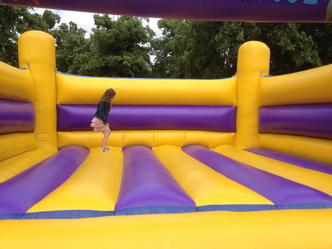 A young girl  playing inside a colorful, inflated moon bounce structure.