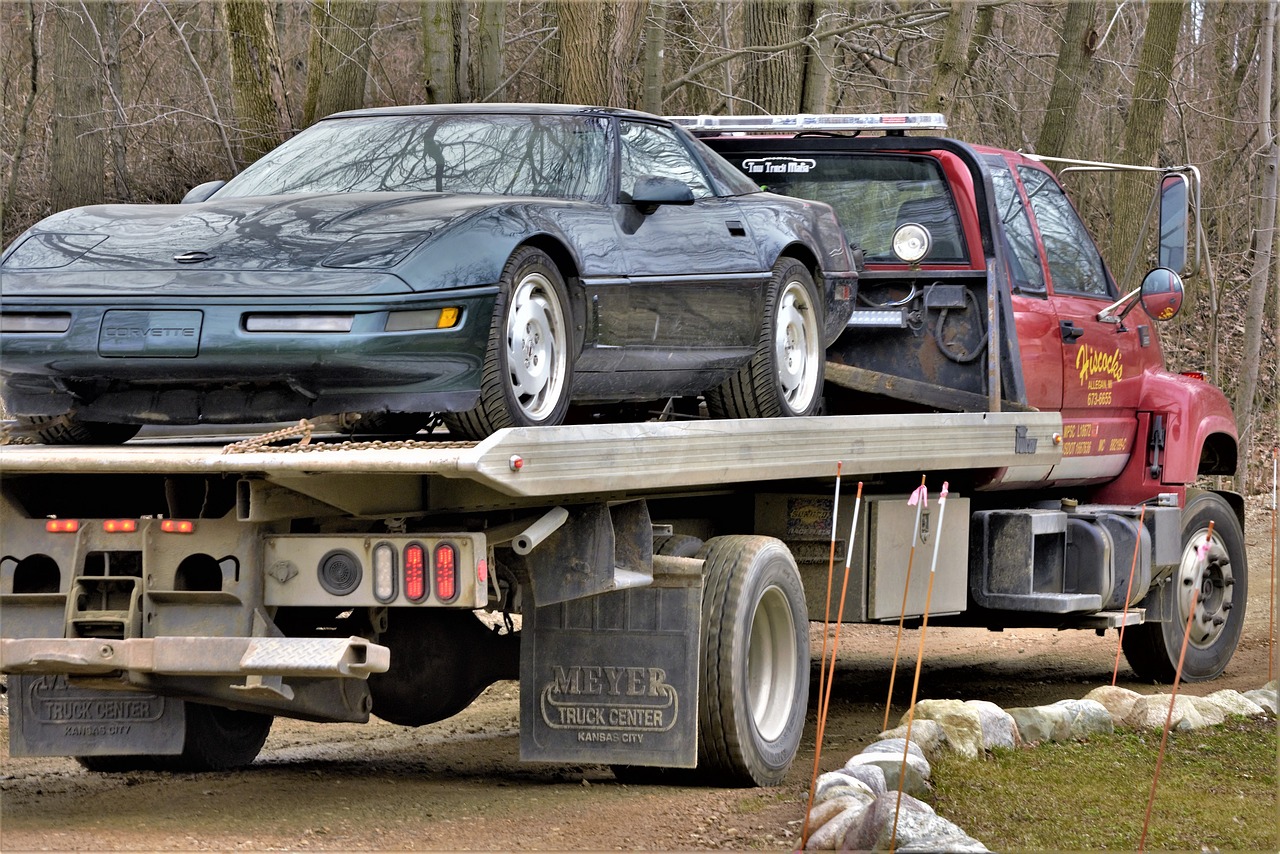 A sleek Corvette sits securely on a flatbed towing truck.