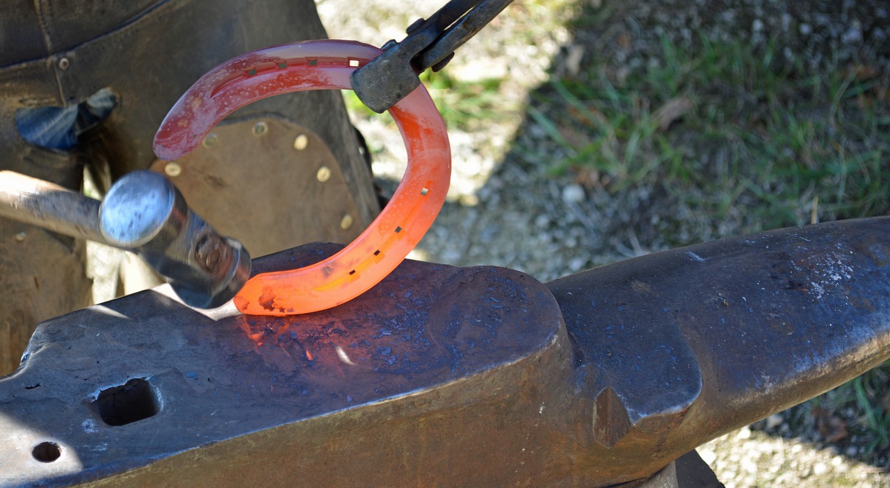Carefully handling a scorching hot horse shoe with tongs