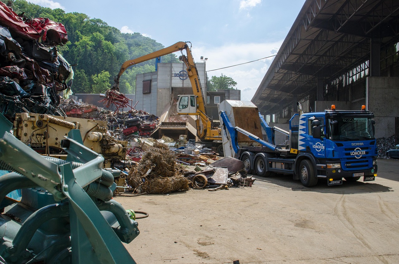 Truck and crane in action at a recycling facility, processing scrap metal for recycling.