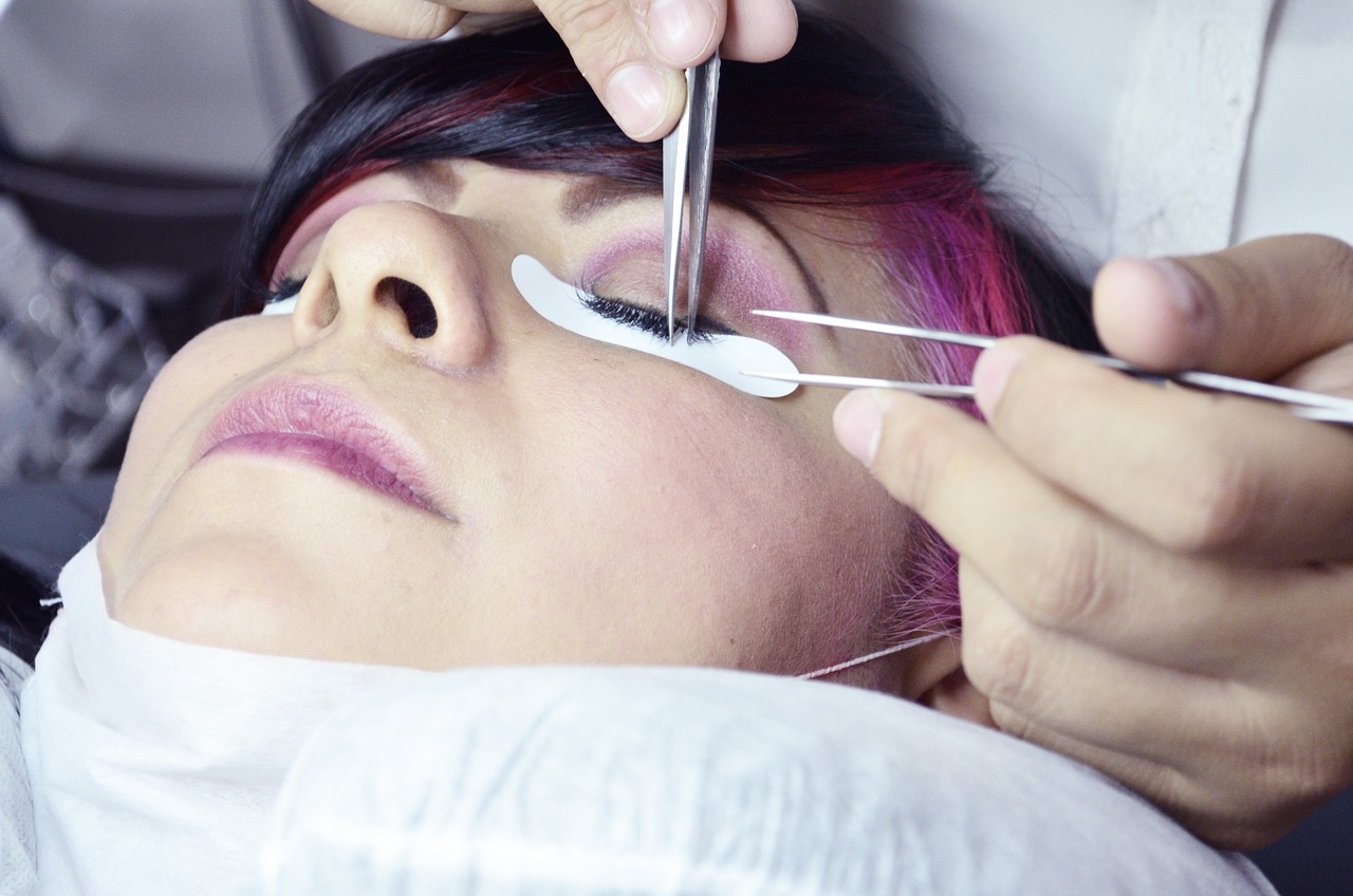 Beauty salon employee carefully attaches eyelashes to a woman's eye