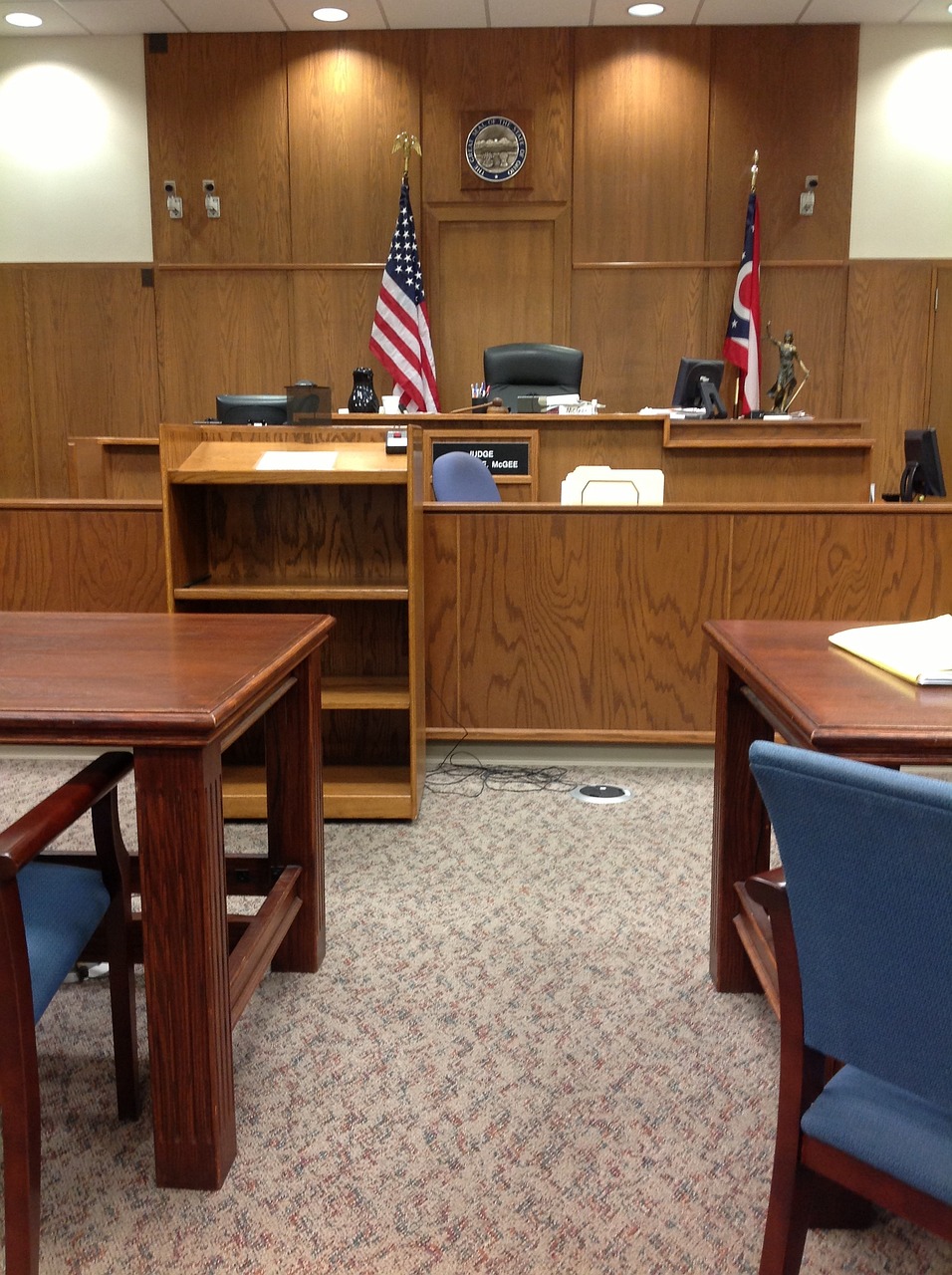 Wood-paneled courtroom with a formal judge's bench and seal of justice.