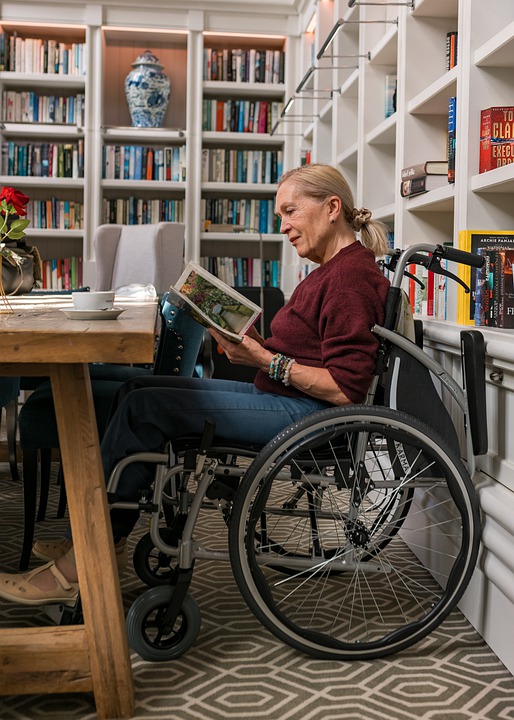 Woman in wheelchair reads in congregate care library