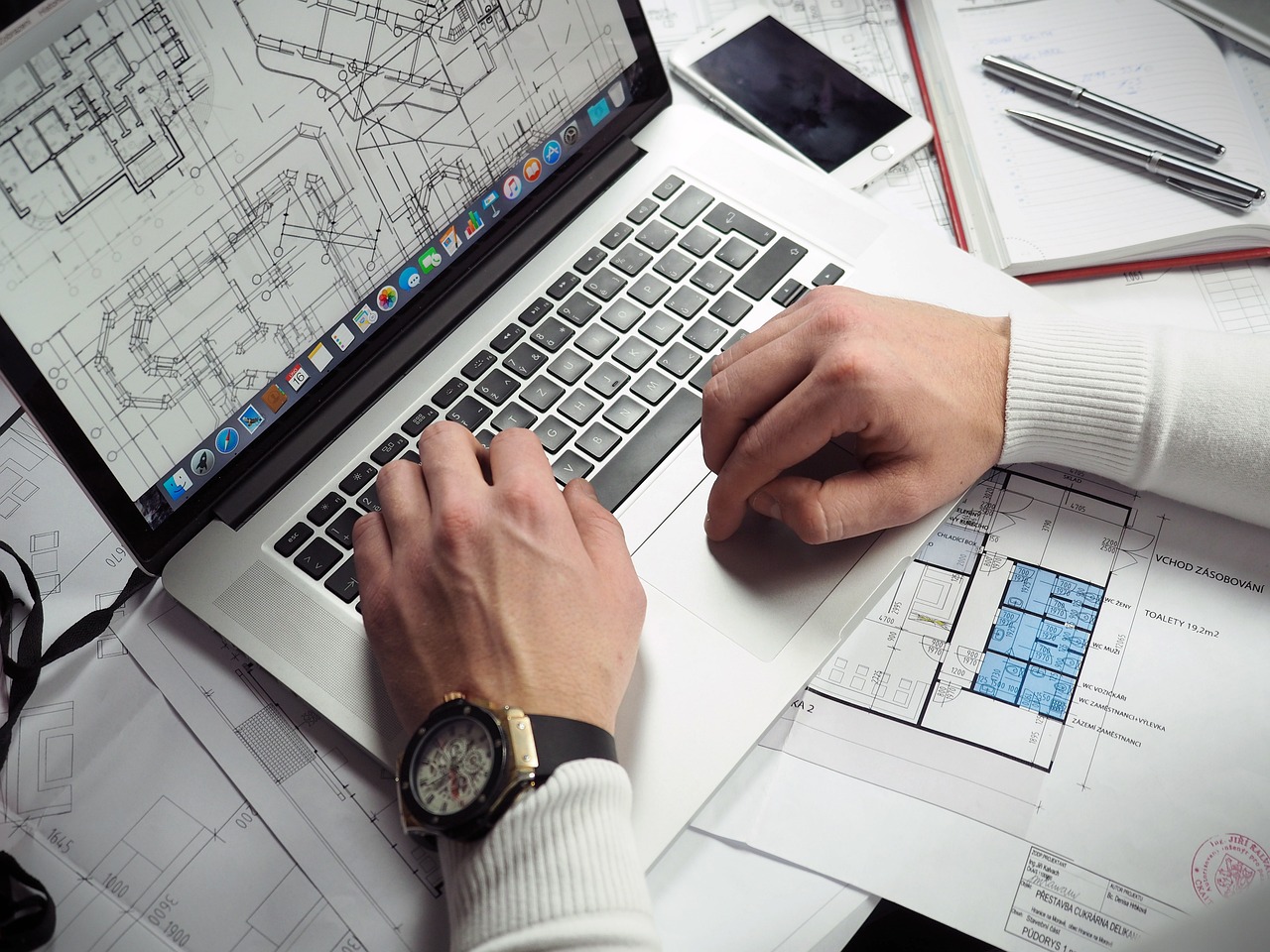 Engineer reviews blueprint designs on laptop.