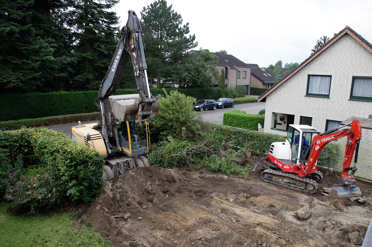 Two excavators precisely grade a residential lot, preparing the land for construction.