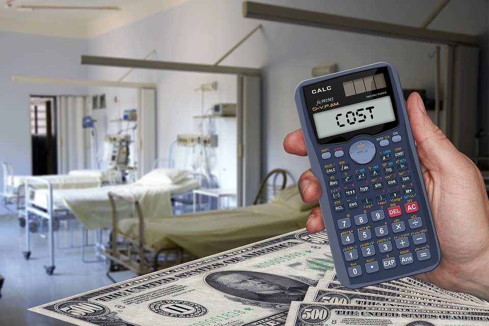 Calculator displaying "cost" in a hospital setting, depicting the rising cost of medical care.