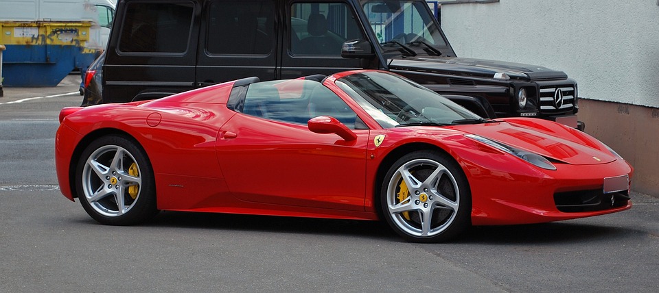 A red Ferrari stands out in a crowded parking lot