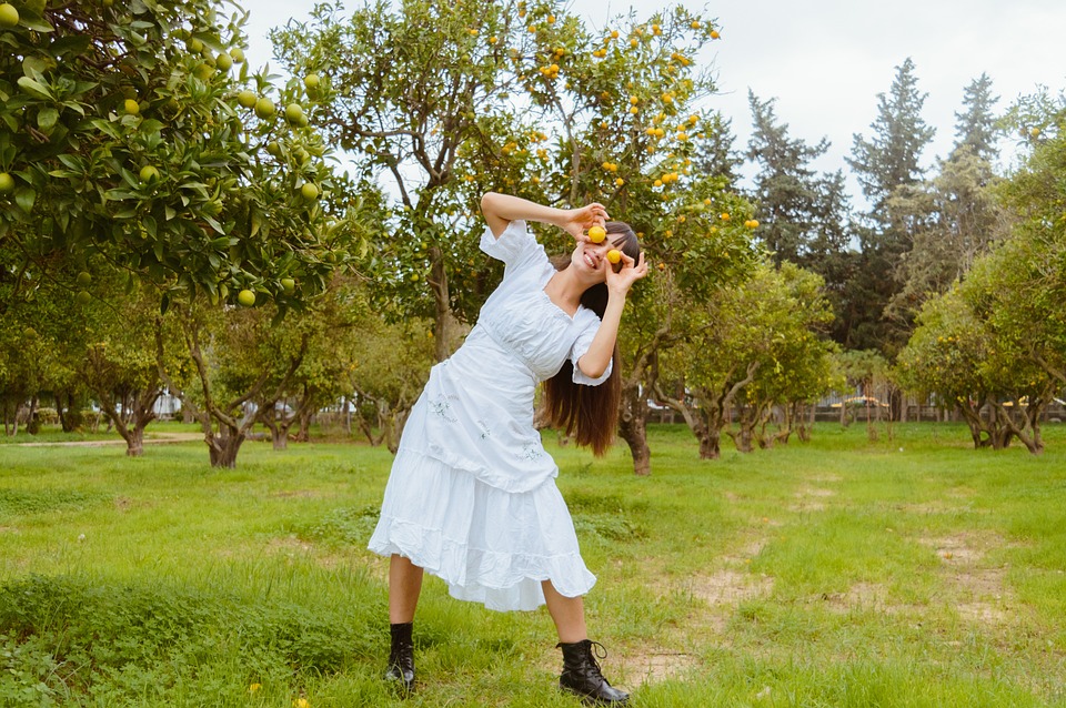 Farmer proudly holds up freshly harvested oranges in a lush orchard."