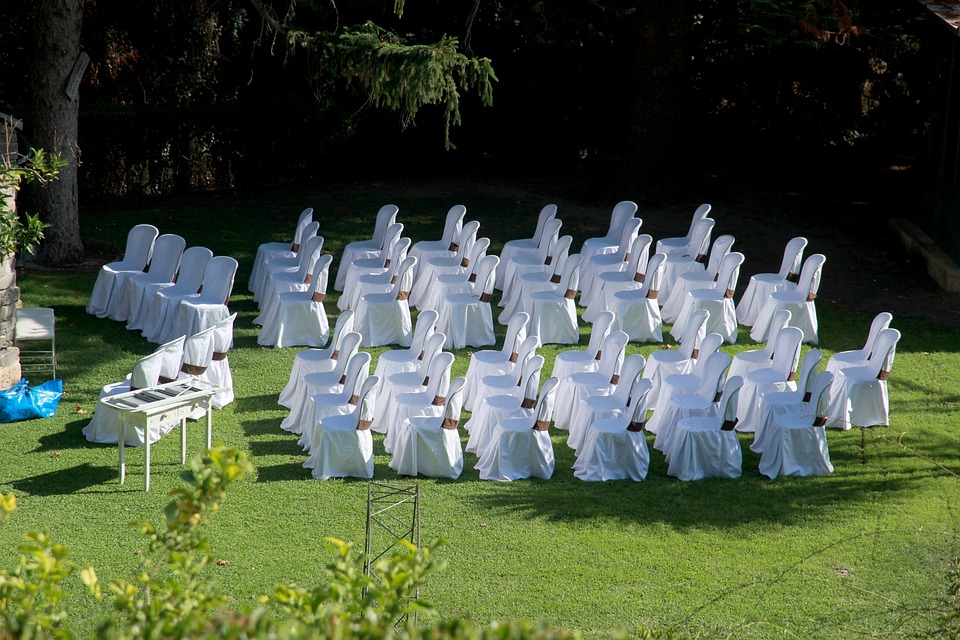 Elegant chairs arranged on a lawn for an outdoor wedding ceremony.