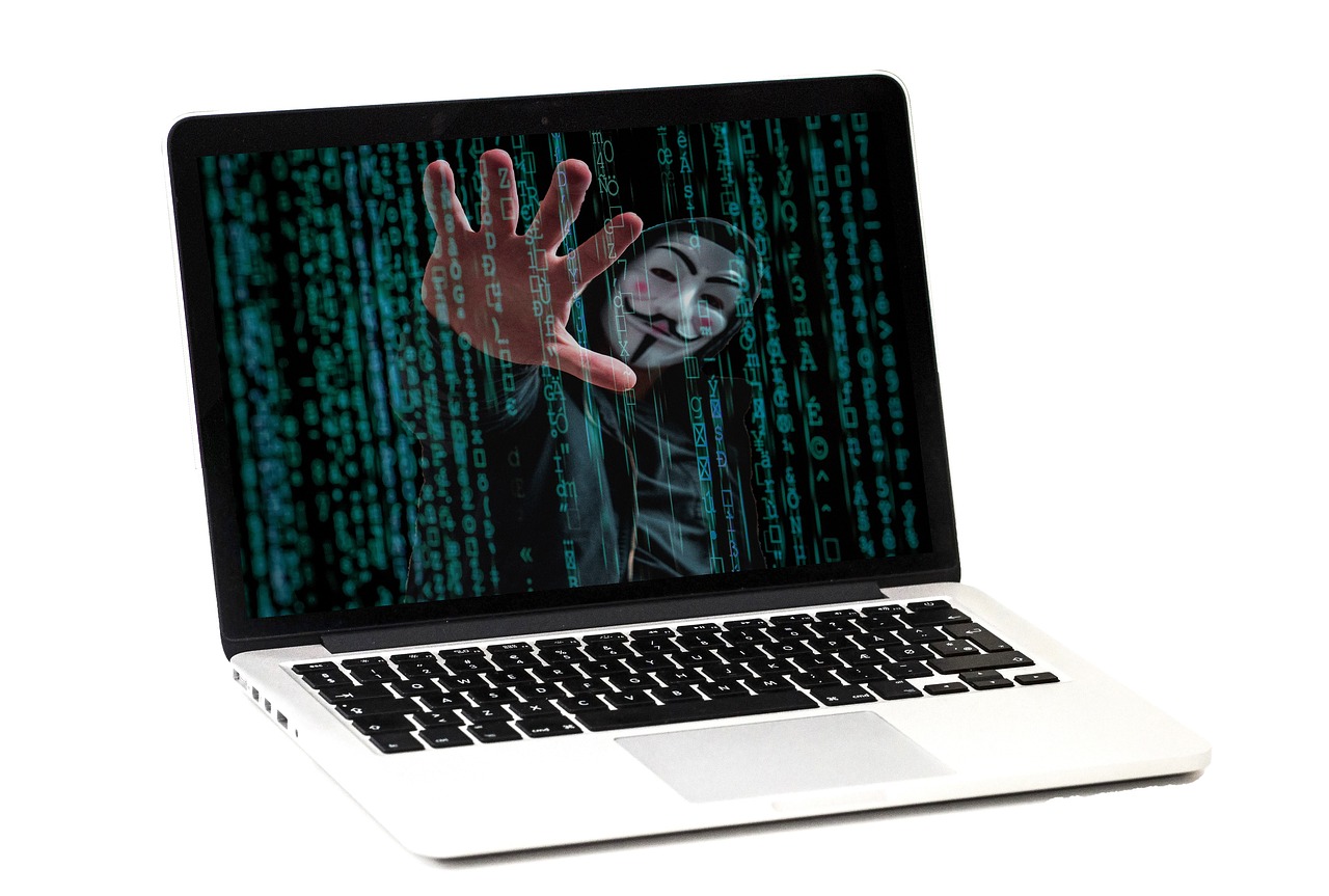 A laptop screen displays a mysterious figure, warning of a potential data breach or cyber threat.