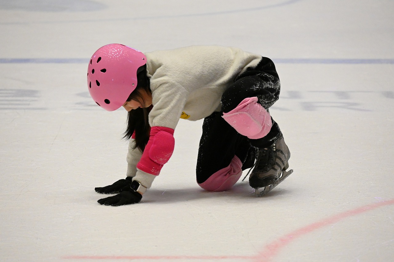 Young girl falls during a trainee session at the ice skating rink