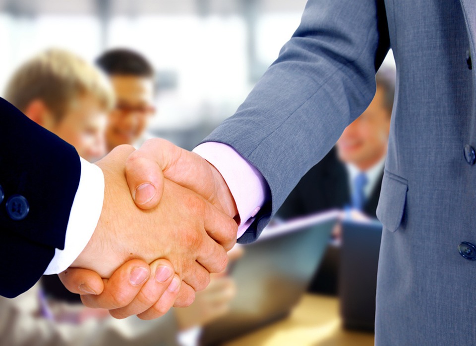 Two individuals shake hands, symbolizing trust, partnership, and agreement.