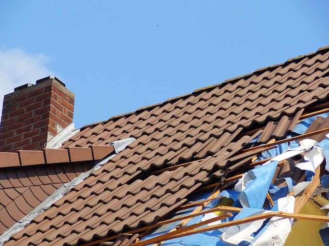 Storm-damaged residential building with torn tile roof and debris