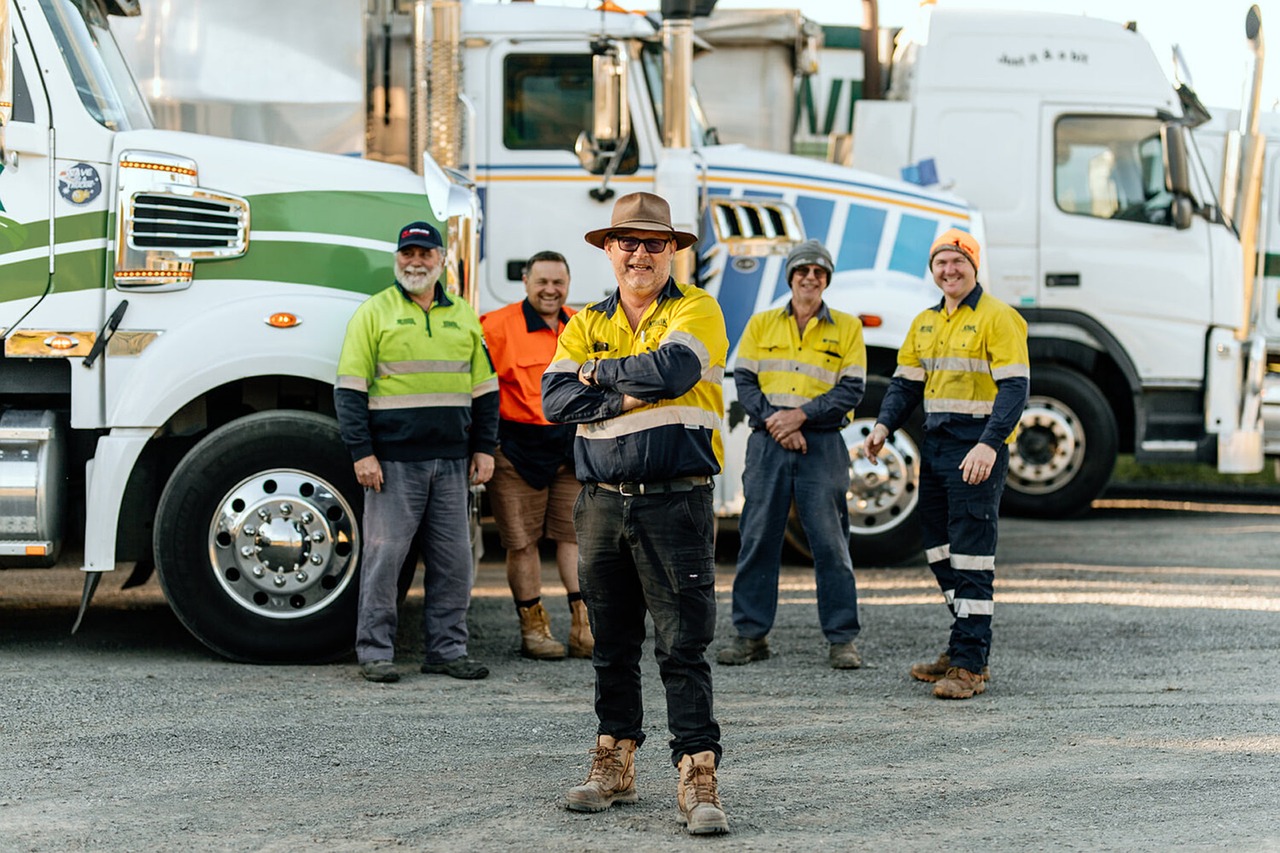 Happy truck drivers posing with their long-haul rigs.