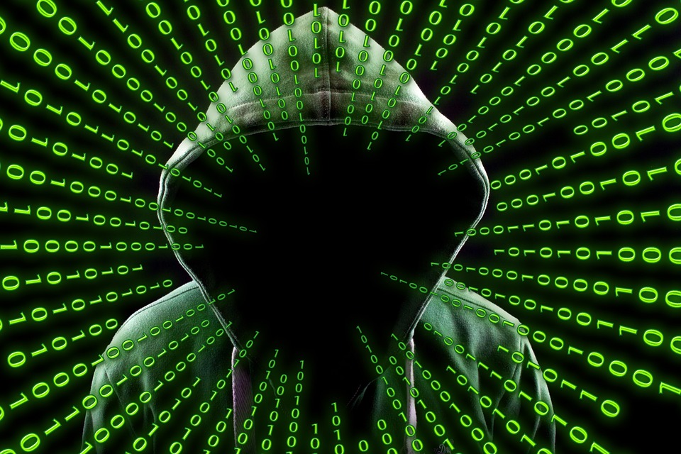 Dark web hacker surrounded by glowing green code.