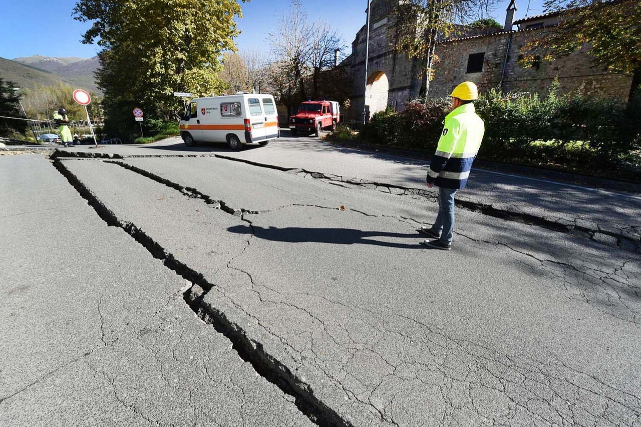 First responders assess earthquake damage, including road cracks, after a seismic event.