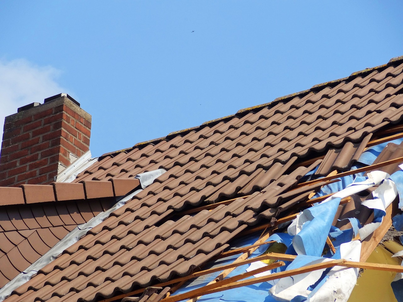 Motel roof damaged with missing and broken tiles after a storm.