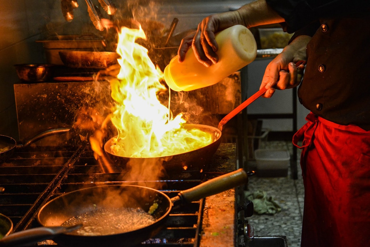 Chef expertly cooking with flames in a sizzling pan.
