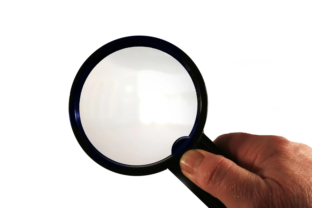 A hand holds a magnifying glass