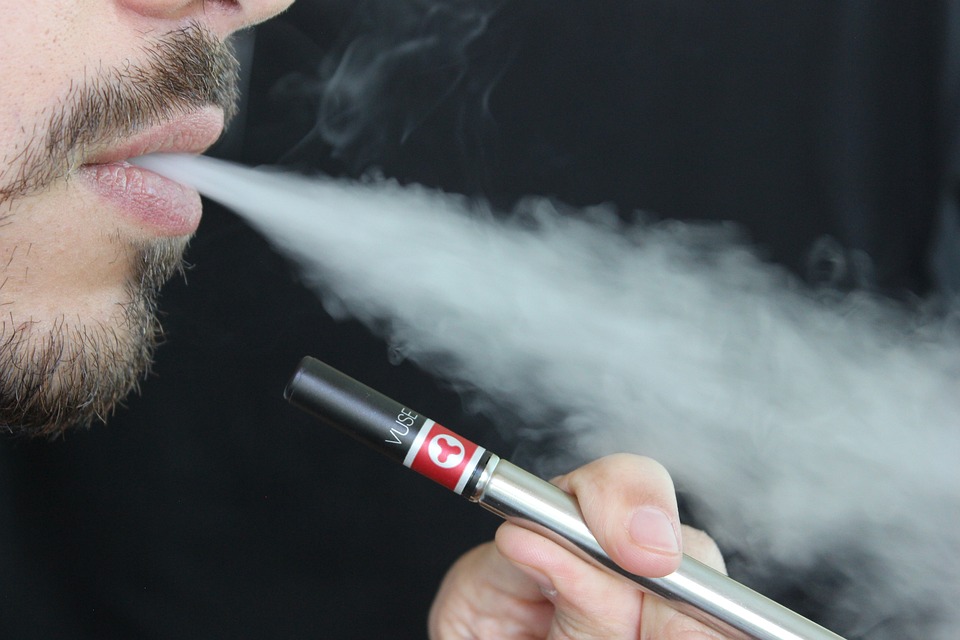 Man vaping and exhaling a cloud of smoke